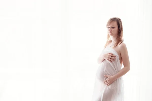 Beautiful young pregnant woman wrapped in white fabric — Stock Photo, Image