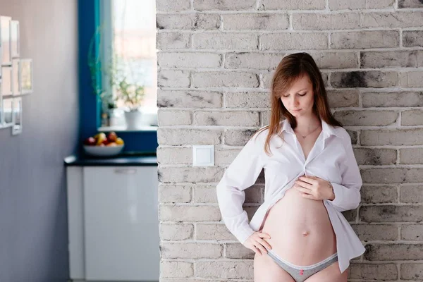 Vacker ung gravid kvinna poserar vid tegelväggen — Stockfoto