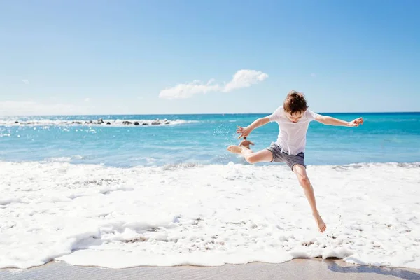 Szczęśliwa 7 lat chłopiec skoki na plaży — Zdjęcie stockowe