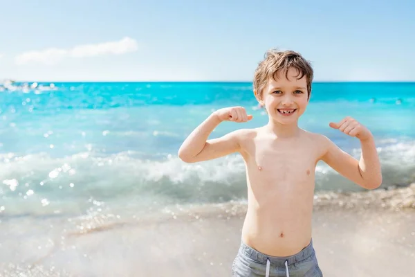 Feliz niño de 7 años en el gesto de éxito victoria en la playa . — Foto de Stock