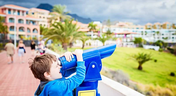 Malý chlapec dítě hraje s dalekohledem veřejných telefonních — Stock fotografie