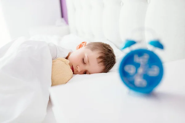 Weinig jongenskind slapen in bed. Knuffelen zijn favoriete teddybeer — Stockfoto