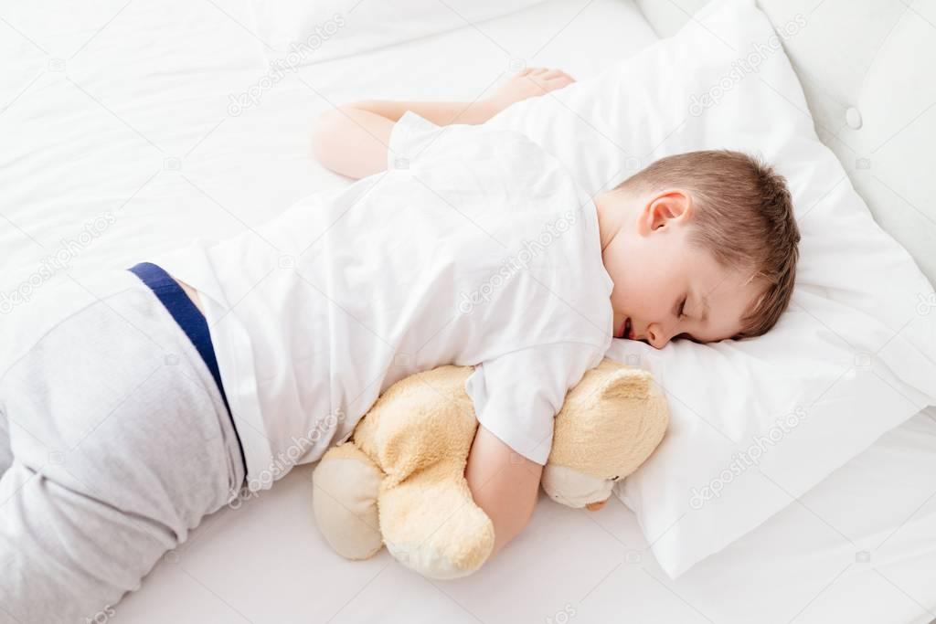 Little boy child sleeping in bed on his stomach