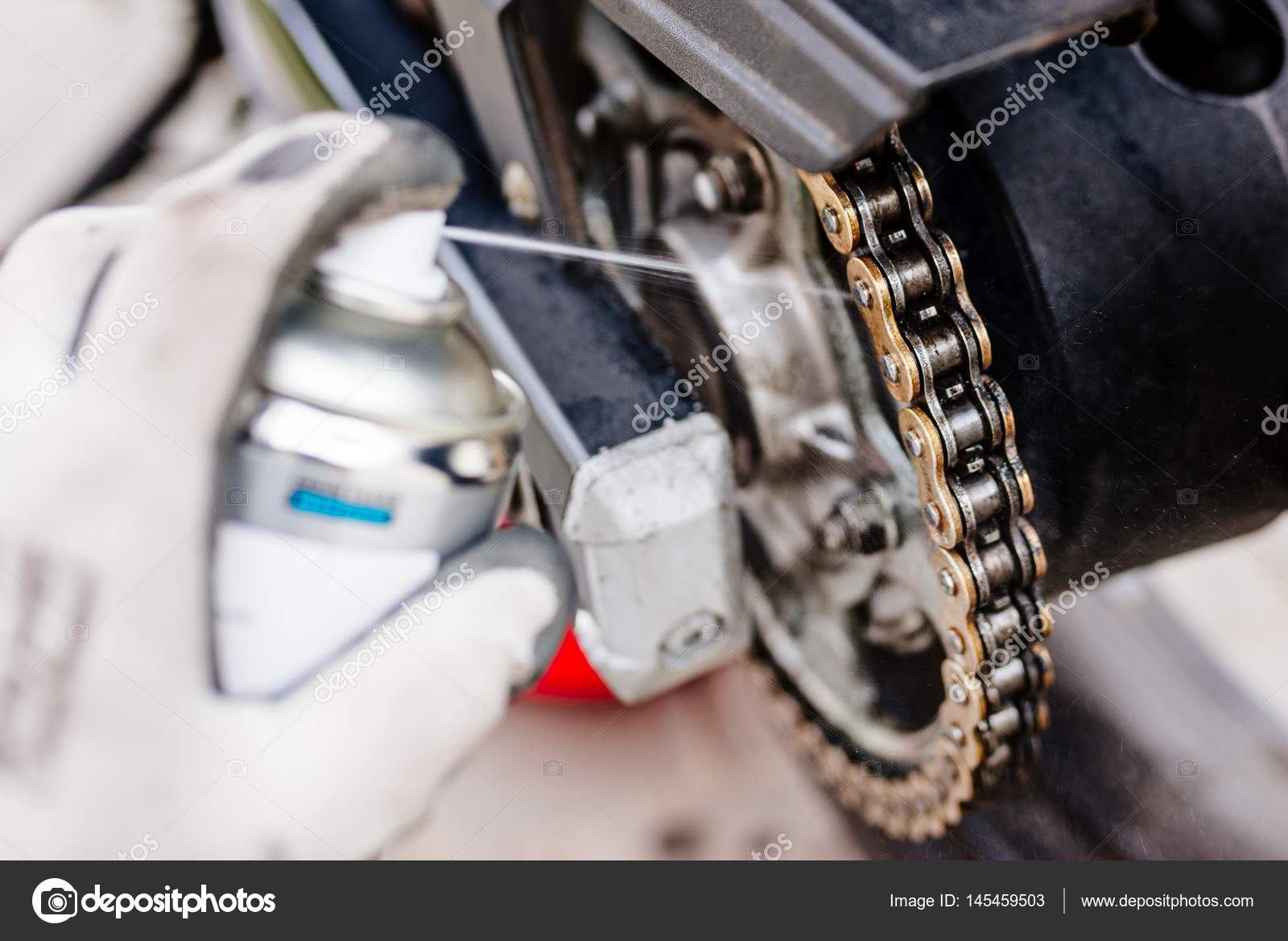 Lubricating motorcycle chain Stock Photo by ©djedzura 145459503
