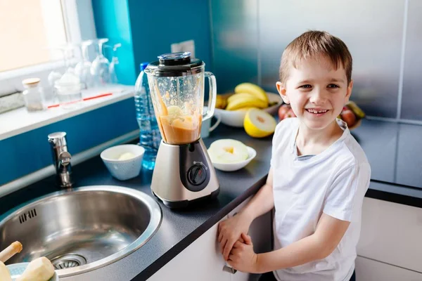 Feliz niño preparando cóctel de frutas en la cocina — Foto de Stock