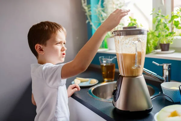 Kleiner Junge fügt ein Stück Melone zum Mixer hinzu — Stockfoto