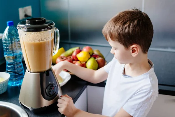 Menino feliz está fazendo suco de fruta saudável em casa — Fotografia de Stock