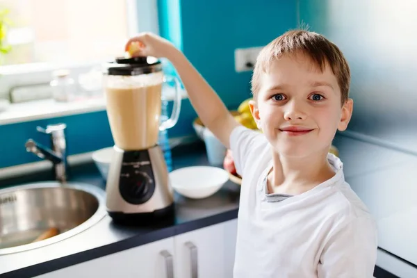 Menino feliz está fazendo suco de fruta saudável em casa — Fotografia de Stock