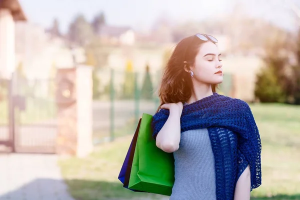 Meisje in blauwe wollen omslagdoek houden papieren draagtassen. — Stockfoto