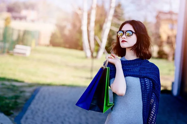 Girl in blue woolen shawl holding paper shopping bags. — Stock Photo, Image