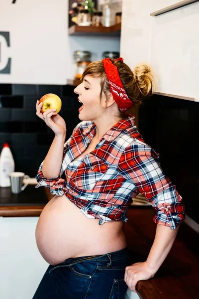 Pin-up estilo joven feliz mujer embarazada comiendo manzana — Foto de Stock