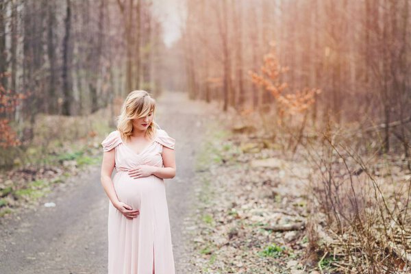Happy pregnant woman relaxing and enjoying life in nature forest at spring
