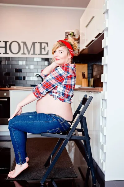 Porträtt av ung glad gravid kvinna på stol i köket. — Stockfoto