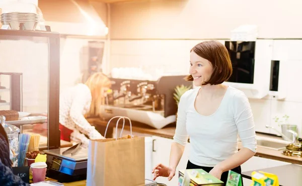 Satisfied female owner of a local store stands smiling behind the counter — Stock Photo, Image