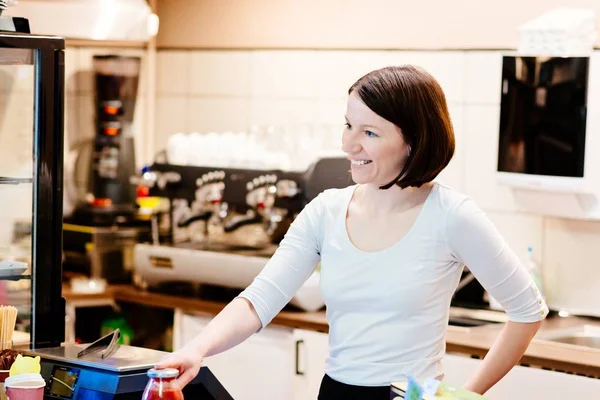 Satisfied female owner of a local store stands smiling behind the counter — Stock Photo, Image