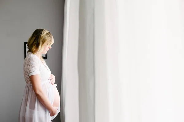 Будущая мама - беременная женщина, стоящая перед окном — стоковое фото