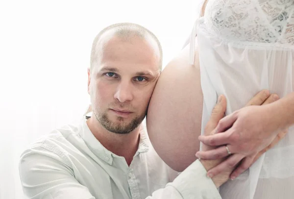 Le mari écoute le ventre de sa femme enceinte — Photo