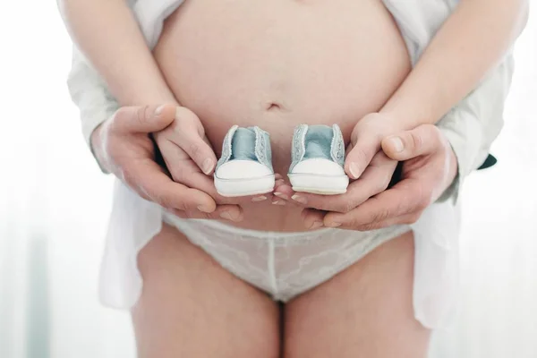 Future maman et papa tenant des chaussures de bébé — Photo