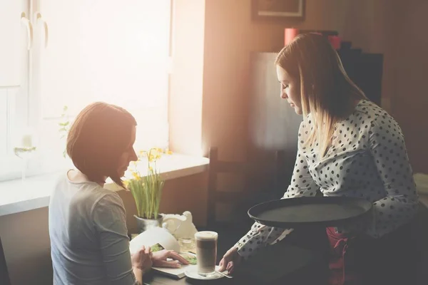 Young waitress in apron serving coffee latte — Stock Photo, Image