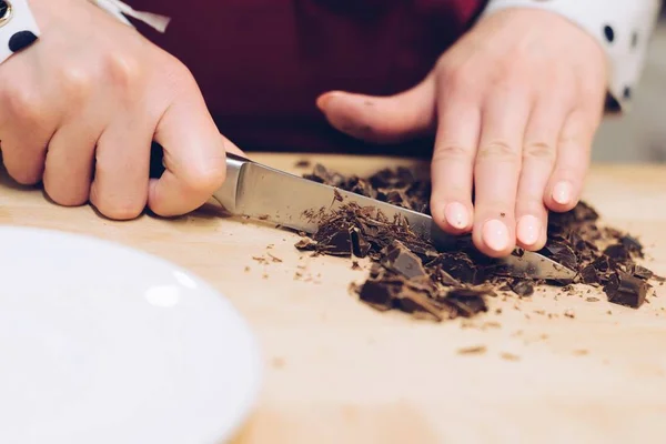 El empleado del café corta el chocolate en trozos pequeños . —  Fotos de Stock