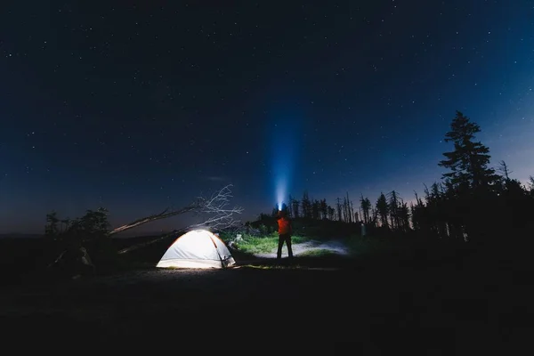 Turista con torcia vicino alla sua tenda campo di notte — Foto Stock