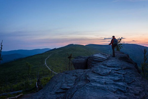 Man tourist with trekking on top of hill