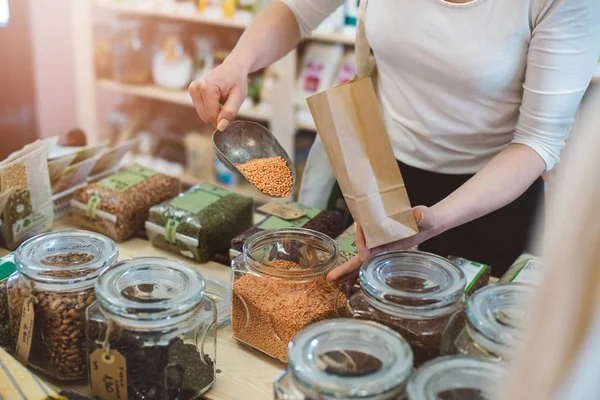 Woman puts lentil seeds into a paper bag