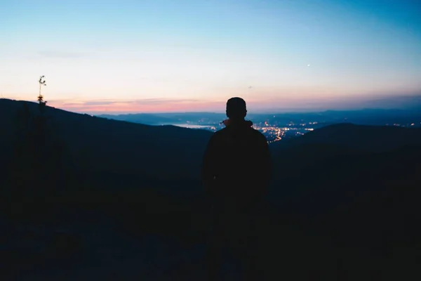 Alone homem turista caminhante olhando para as luzes da cidade a partir da colina — Fotografia de Stock
