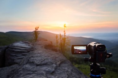 Dağlar gündoğumu filme tripod üzerinde dijital video kamera.