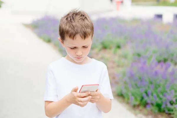 子供男の子彼のスマート フォンでモバイル ゲームをプレイ — ストック写真