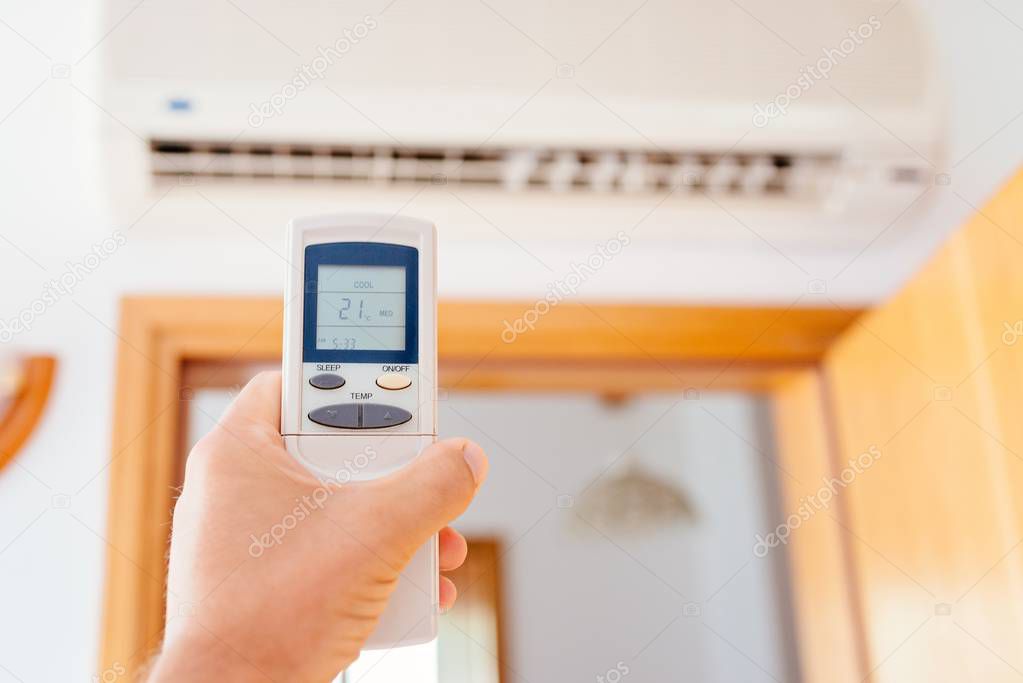 Close up on male hand adjusting home air condition