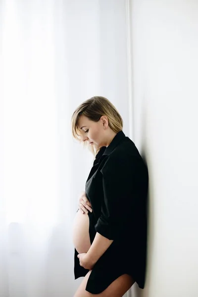 Beautiful young pregnant standing next to window — Stock Photo, Image