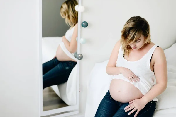 美丽的年轻怀孕女子，看着她的肚子 — 图库照片