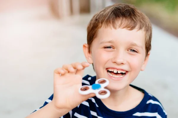 Little child boy playing with fidget spinner outdoors — Stock Photo, Image