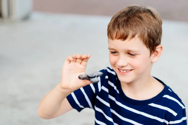Little child boy playing with fidget spinner outdoors — Stock Photo, Image