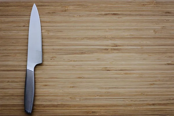 Stainless kitchen knife on empty cutting board. — Stock Photo, Image