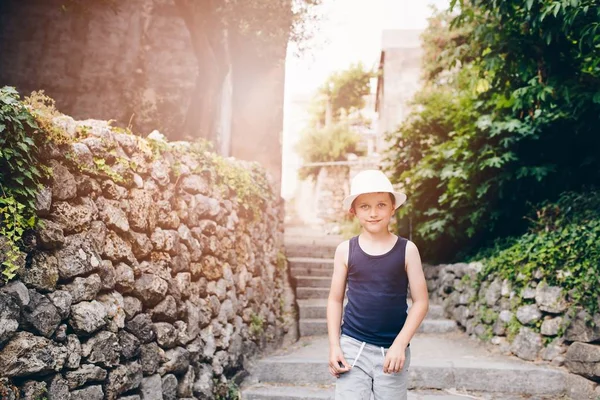 Niño en sombrero blanco caminando en la calle estrecha del casco antiguo — Foto de Stock