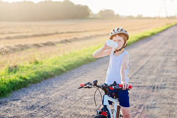 Хлопчик у велосипедному шоломі п'є пляшкову воду — стокове фото