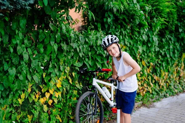 Щасливий хлопчик у велосипедному шоломі накачує колесо на своєму велосипеді — стокове фото
