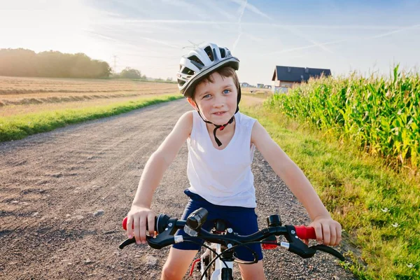 Щасливий хлопчик у велосипедному шоломі на своєму велосипеді . — стокове фото
