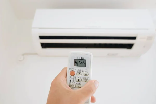 Hand adjusting temperature of home air conditioner