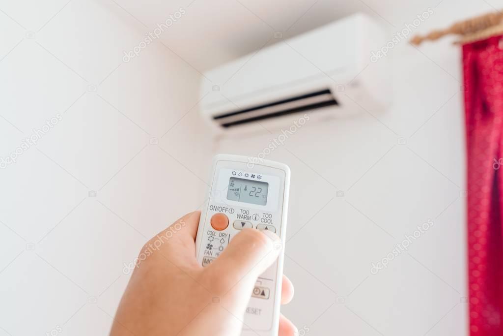 Hand adjusting temperature of home air conditioner