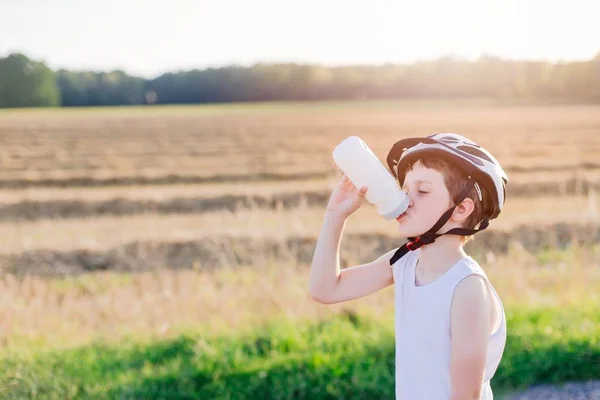 Jongenskind in witte fiets helm drinkwater — Stockfoto