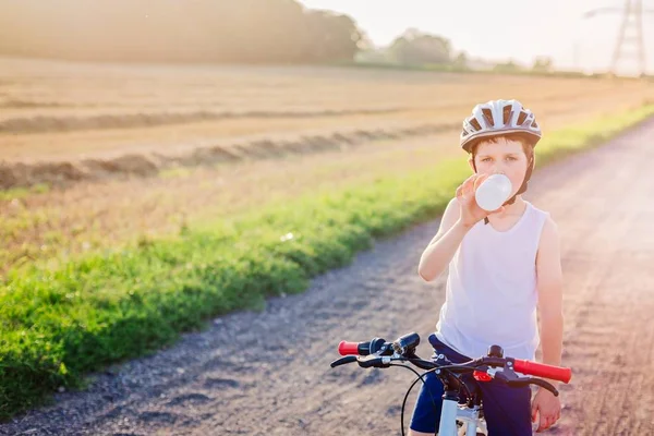 Boy child in white bicycle helmet drinking water — Stock Photo, Image