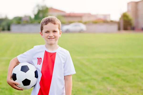 Хлопчик тримає футбольний м'яч на ігровому полі . — стокове фото