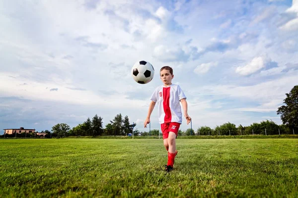 Niño jugando con pelota de fútbol en el campo de juego . —  Fotos de Stock