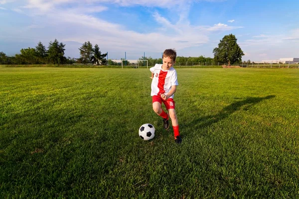 Niño jugando con pelota de fútbol en el campo de juego . —  Fotos de Stock