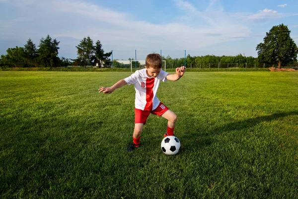 Niño jugando con pelota de fútbol en el campo de juego . —  Fotos de Stock