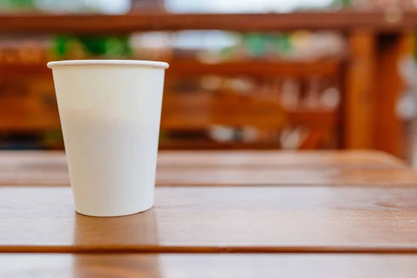 Witboek coffee cup op houten tafel buiten. — Stockfoto