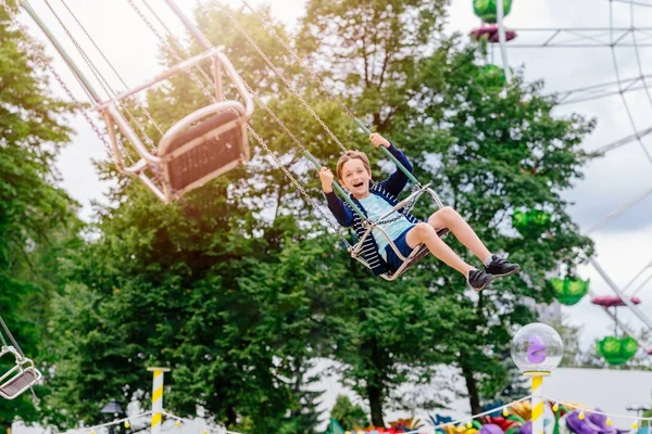 Menino feliz se divertindo no parque de diversões . — Fotografia de Stock